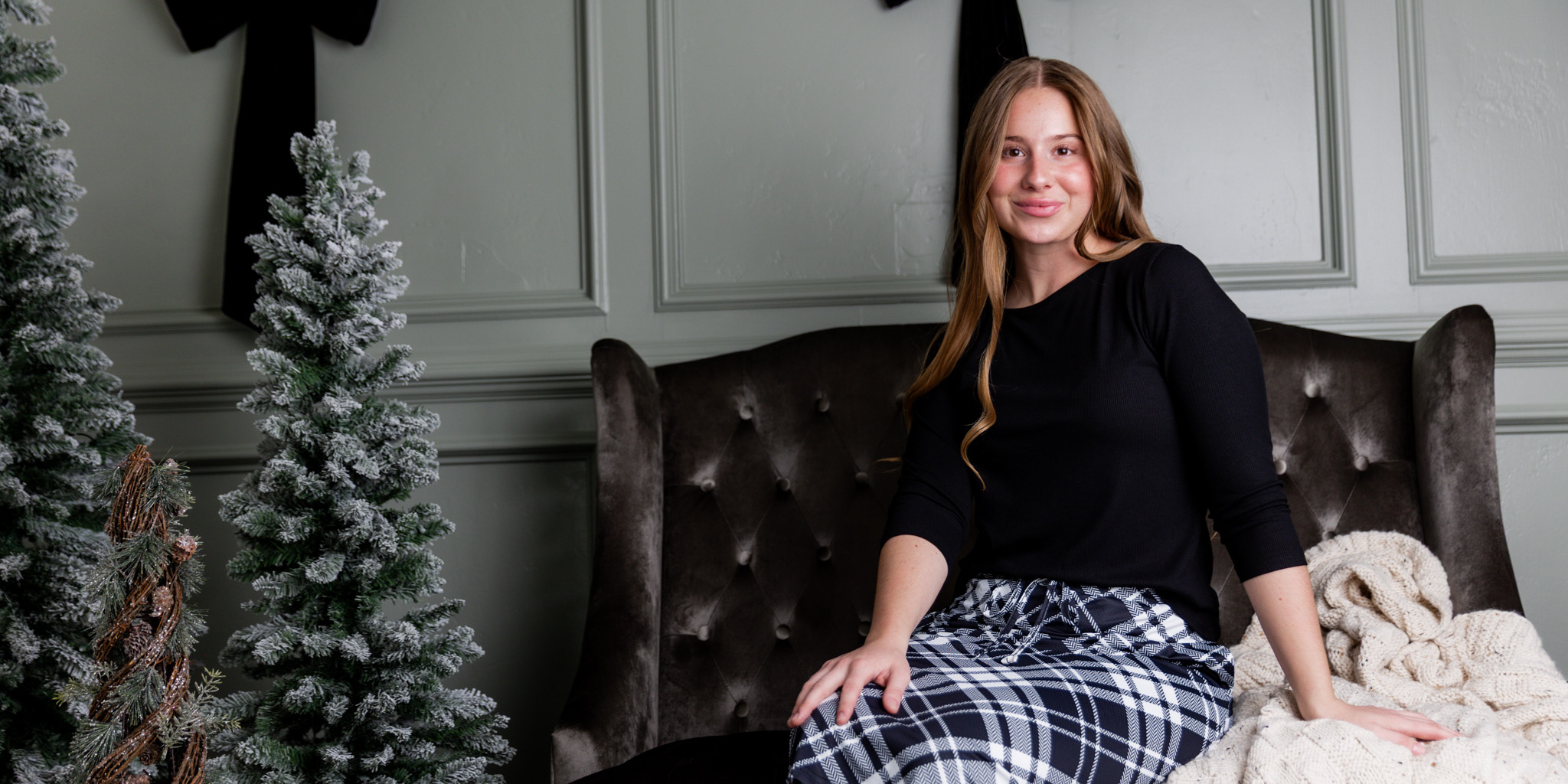 A woman sitting on a couch wearing nuggles modest tee and sport flex skirt.