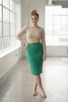 Women wearing a kelly green classic 27" midi length skirt with a beige shirt in a sunlight loft.