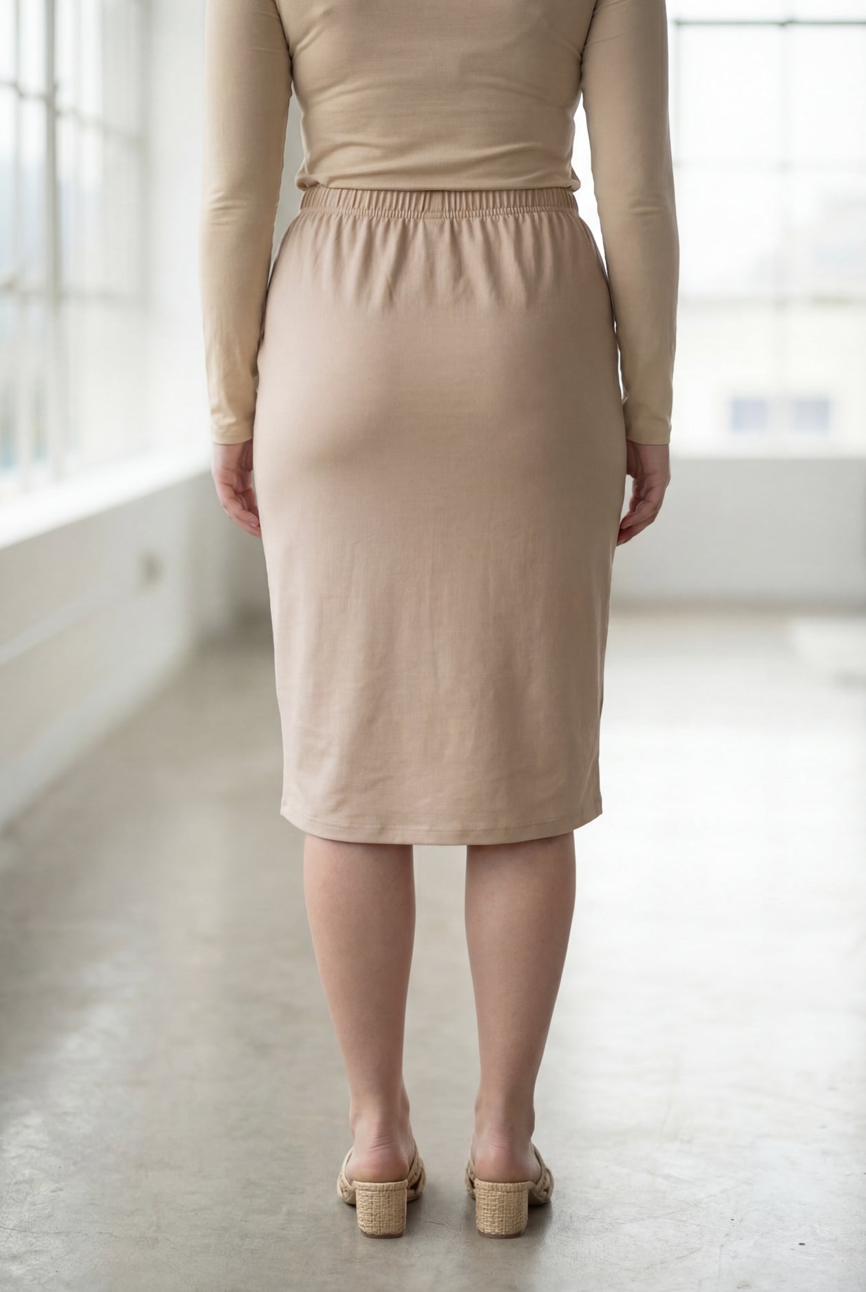 Women wearing a khaki classic 27" midi length skirt with a beige shirt in a sunlight loft.
