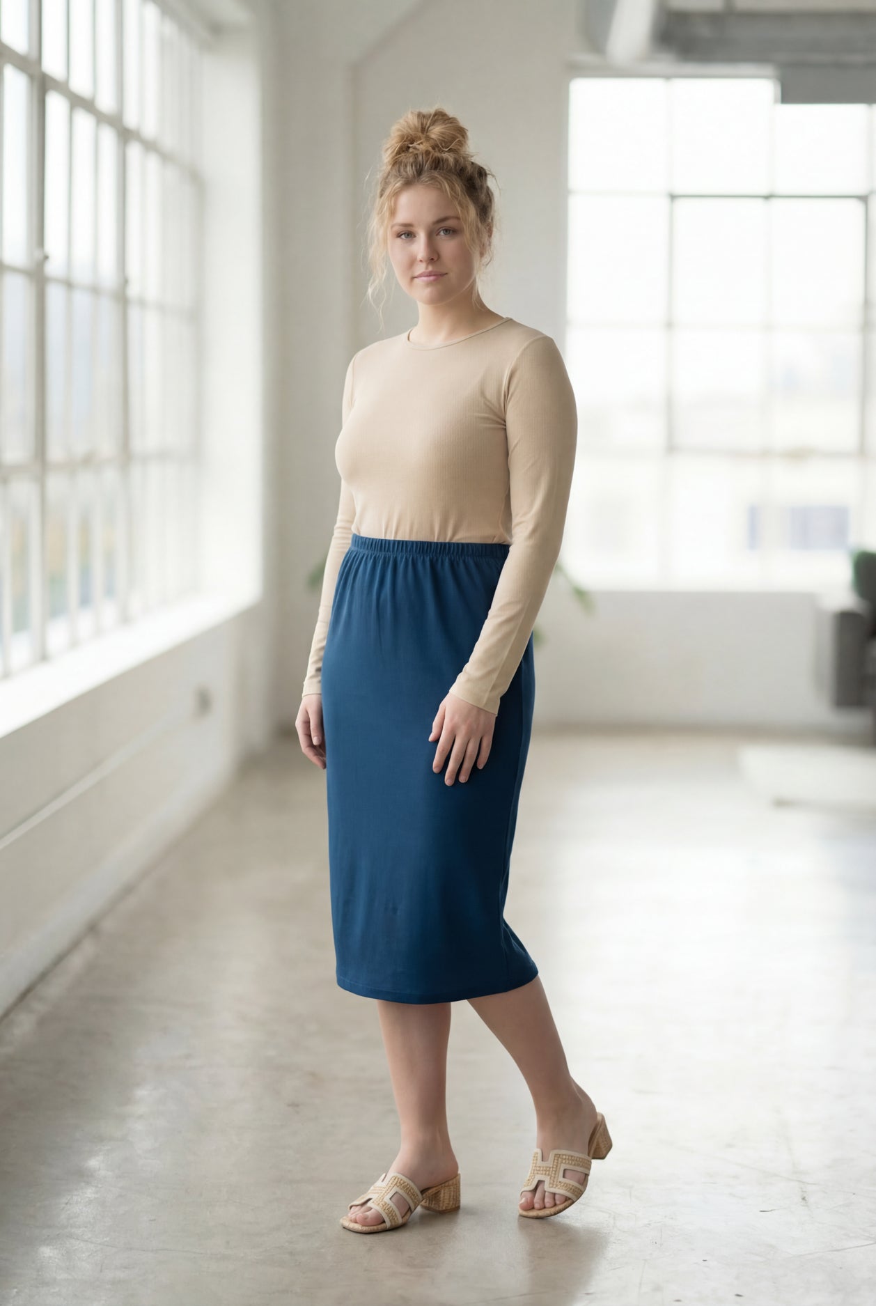 Women wearing a peacock blue classic 27" midi length skirt with a beige shirt in a sunlight loft.