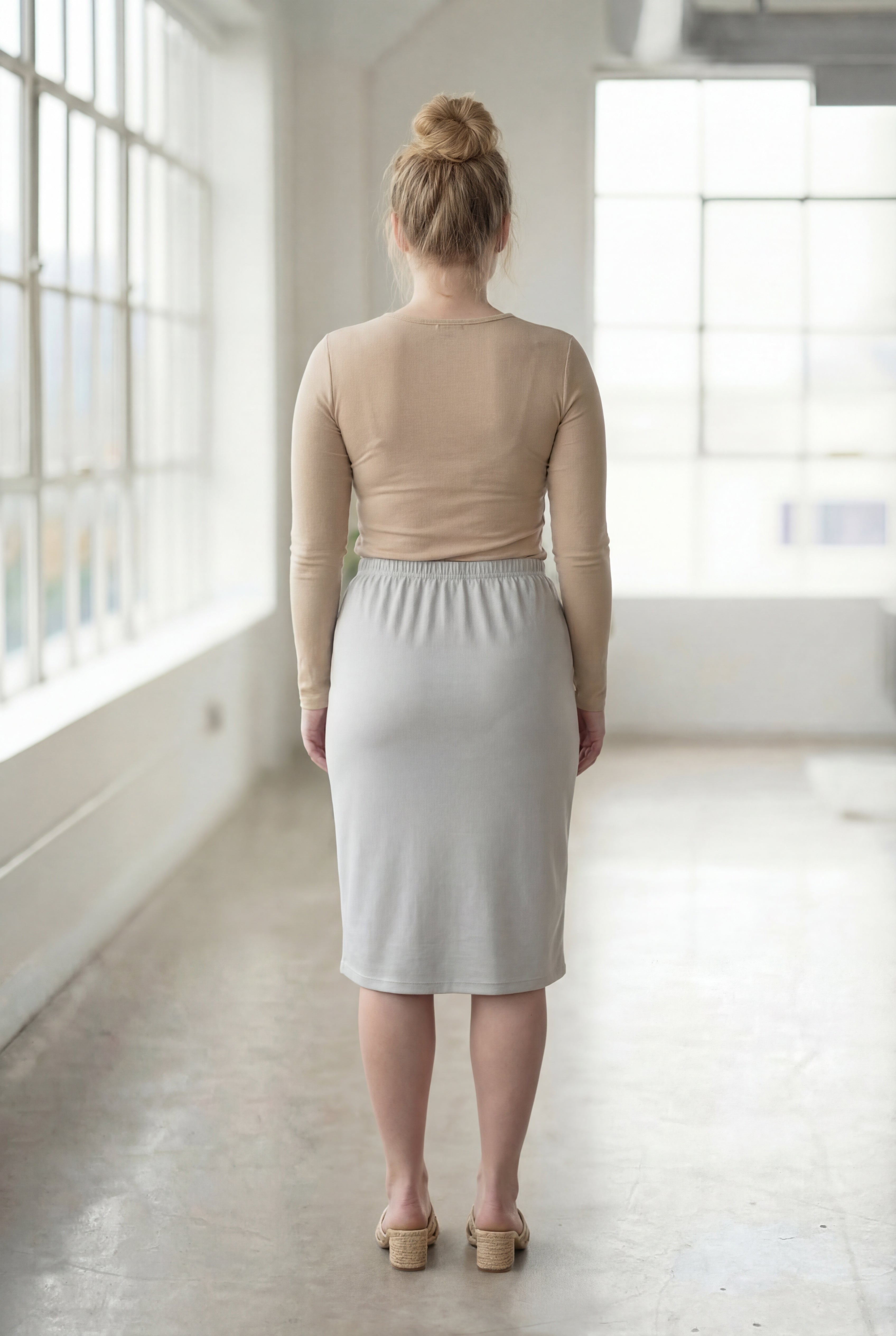 Women wearing a silver classic 27" midi length skirt with a beige shirt in a sunlight loft.