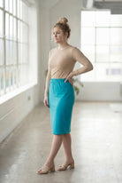 Women wearing a teal classic 27" midi length skirt with a beige shirt in a sunlight loft.